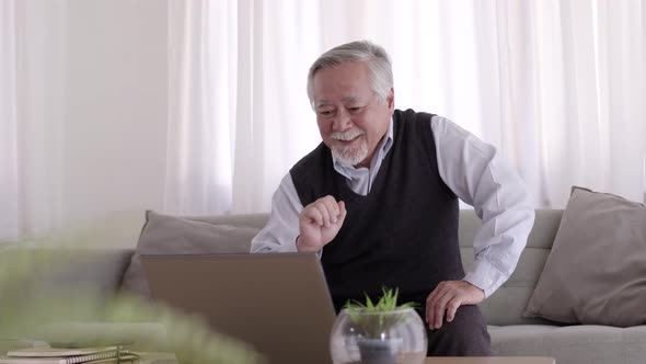 An Asian Elderly man Happy after a successful on online job.