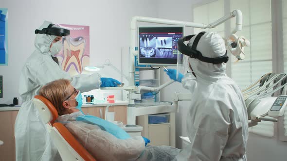 Orthodontist in Special Equipment Pointing on Digital X-ray