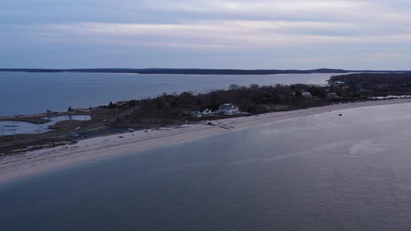 an aerial view over a narrow beach in Orient Point, New York during a cloudy sunset. The camera doll