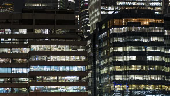 Busy office building windows at night lighting up time lapse