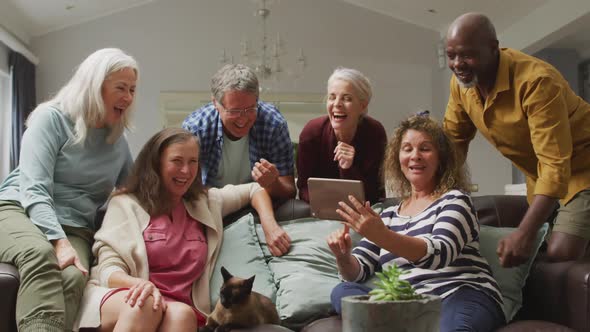 Animation of happy diverse female and male senior friends using tablet at home