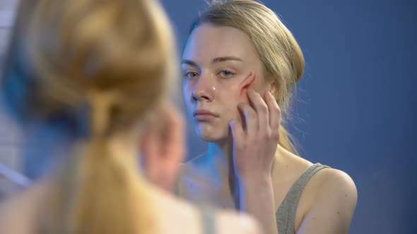 Sad Female Victim Looking at Face Wound in Mirror, Domestic Violence, Abuse