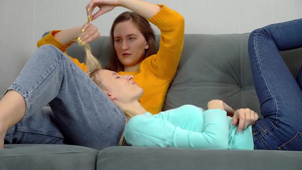 Charming European women lying on the couch fool around and laugh.