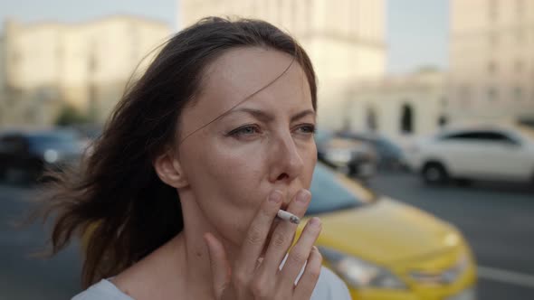 a Closeup of a Female Face on a City Street Against the Background of Passing Cars is Out of Focus