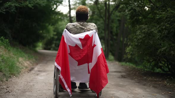 Back View Wide Shot Wheelchair with Canadian Flag and African American Young Man Thinking Admiring