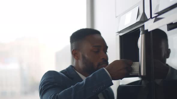 Close Up of African Businessman Making Coffee in Coffee Machine in Office Cafeteria