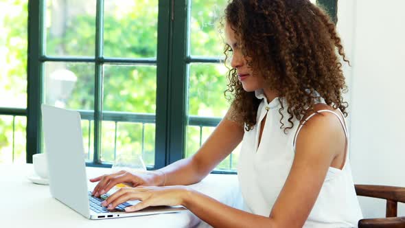 Woman using laptop while having juice