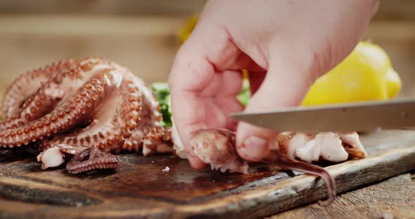 Men's Hands with a Knife Cut Boiled Octopus To Pieces
