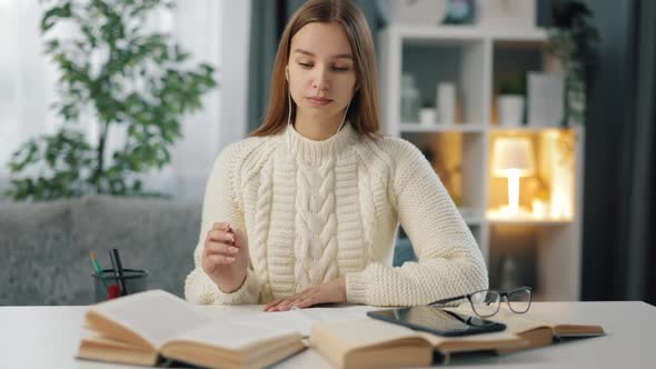 Woman in Earphones Studying at Table