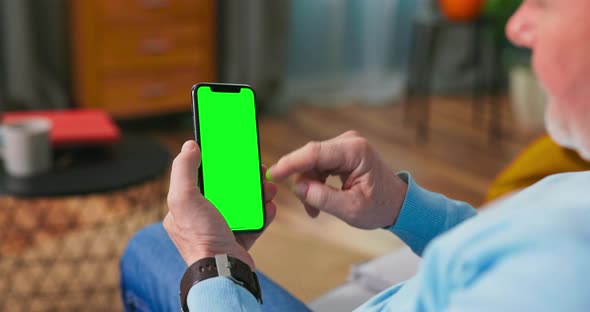 Senior Man at Home Uses Green Mockup Screen Cell Phone