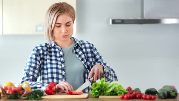 Confident Young Woman Slicing Fresh Red Sweet Pepper on Wooden Board Using Knife Medium Closeup