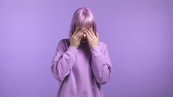 Young Woman Cannot Believe Her Eyes Rubs It and Peers More Closely at Camera on Purple Studio