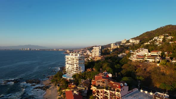 skyline of hotels and resorts on mountain hills in Puerto Vallarta Mexico at sunset, aerial