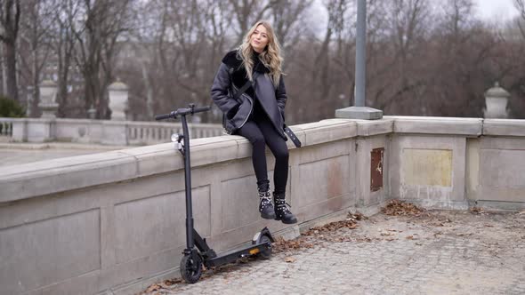 Woman Resting Near Electric Scooter in Park