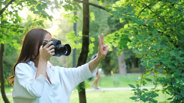 Pretty Girl Photographer in White Shirt Is Making Photos and Before Taking a Picture She Shows on