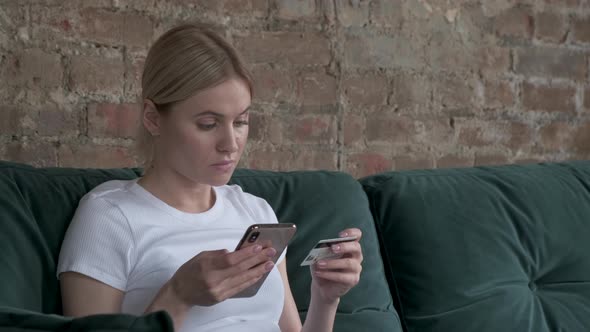 Close-up woman buys online shopping at home with card and phone.