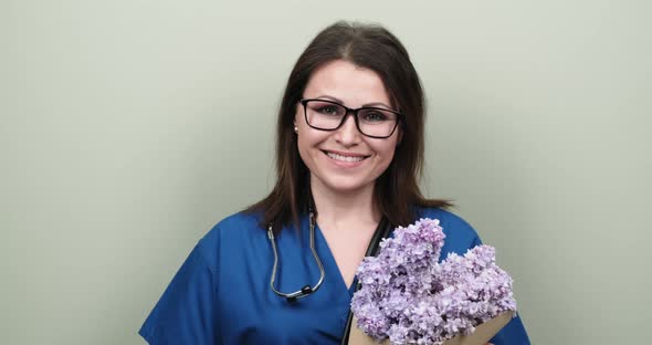 Doctor's Day, Celebration. Happy Smiling Female Medic with Bouquet of Flowers