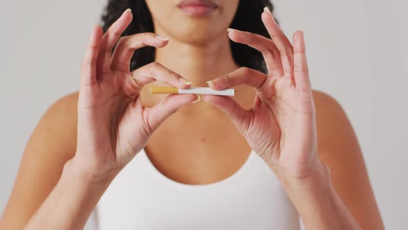 Video of biracial woman holding and breaking cigarette on white background