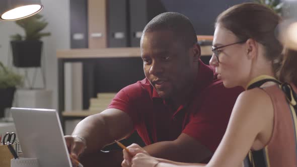 Diverse Colleagues Using Laptop and Talking in Office