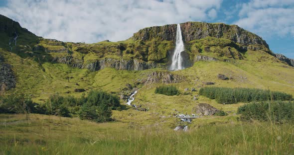 Majestic Scenic Tourist Attraction Bjarnarfoss Waterfall with Its High and Steep Green Cliffs in