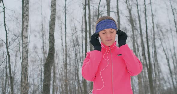 The Girl Before the Morning Winter Jog Inserts Headphones in the Ears and Is Preparing To Run