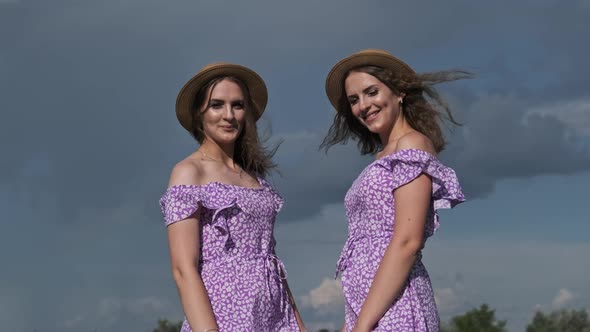 Portrait Two Young Twin Girls in Identical Dresses Looking in Camera in Nature