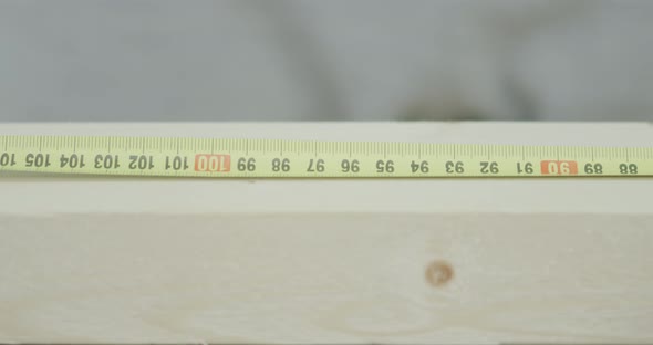 Man Uses Ruler Tape to Mark Wooden Plank Size