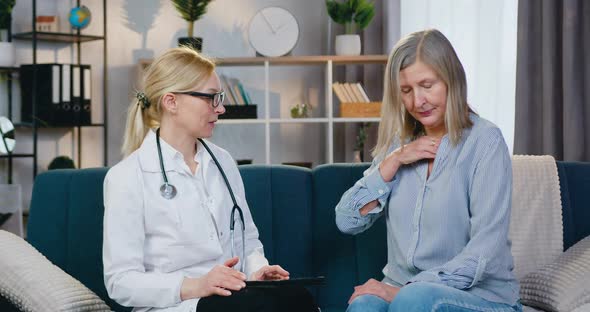 Doctor Sitting Together on the Couch at Home and Talking while Patient Checking Temperature