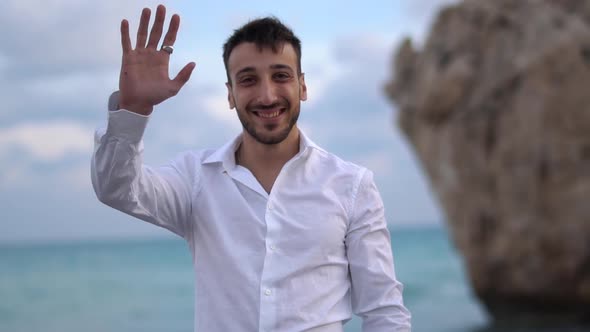 Portrait of a Successful Smiling Man in a White Shirt Waving a Hand