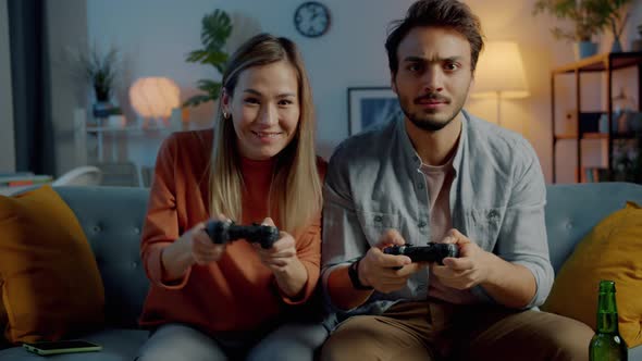 Portrait of Happy Couple Enjoying Video Game and Laughing Together in Illuminated House