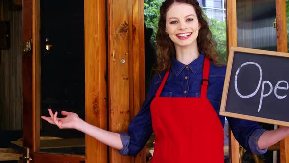 Smiling waitresses holding open sign board