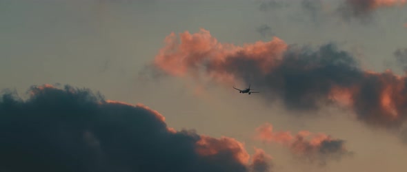 Plane flying in the clouds at sunset, cinematic slow motion, BMPCC 4K