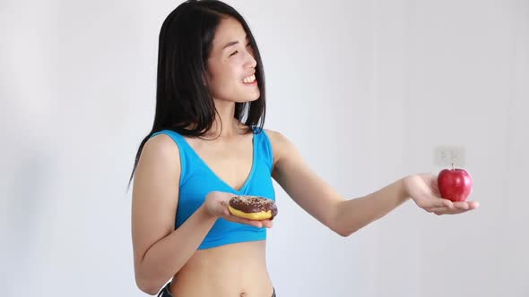 smiling fitness woman holding apple and donut