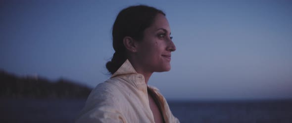 Profile view of a girl smiling and chilling after the sunset on a bench on the pier