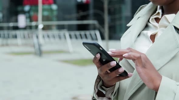 Black woman is using her smartphone outside. Camera is in rotation mode.