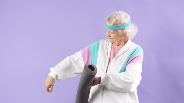 Joyful Old Lady with a Rug Is Going To Practice Yoga Exercises