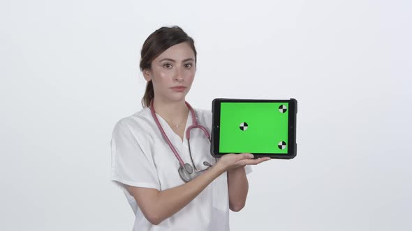 Medical personnel holding and looking at tablet with serious face