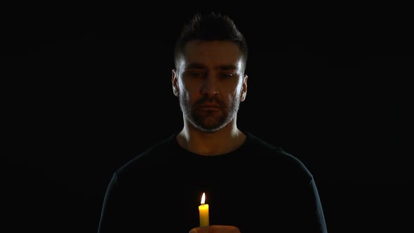 Desperate Crying Man Holding Candle on Black Background, Symbol of Hope, Sorrow