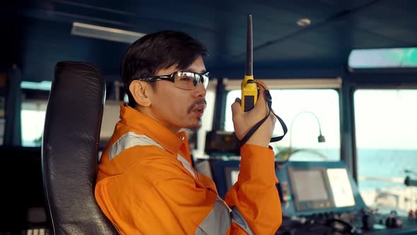 Filipino Deck Officer on Bridge of Vessel or Ship. He Is Speaking on GMDSS VHF Radio