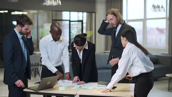 Business Meeting International Management Team at Work Team Is Standing Next To a Work Table and