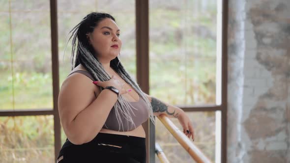 Happy Body Positive Fat Woman with Dreadlocks Doing Stretching in the Gym