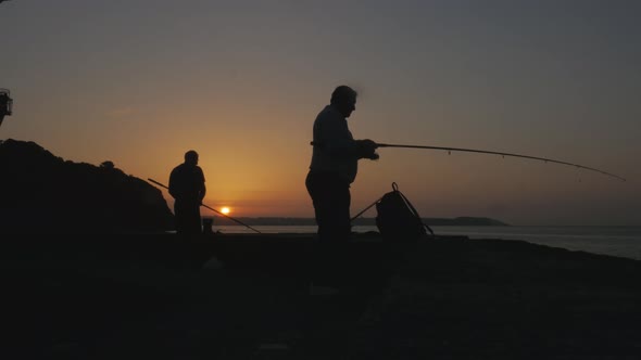 Beautiful silhouette of fishermen casting their rods at sunrise, early bird catches the worm concept