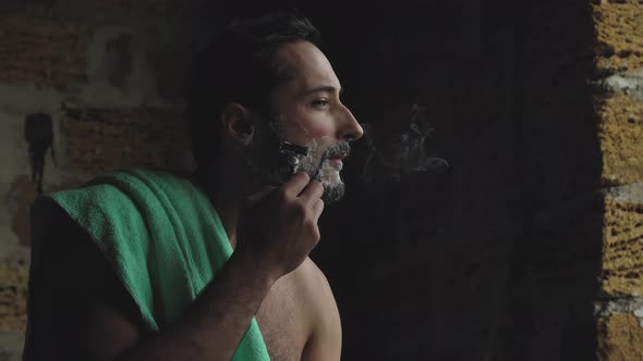 A Man of Latin Appearance Smokes and Smears Shaving Foam on His Face