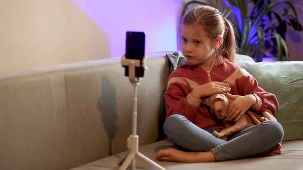 A little blonde blogger girl, leads a live broadcast with a cat, Taking selfies, call friends.