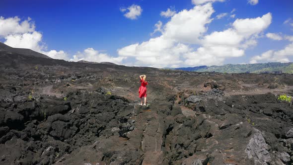 Woman in Red Dress on Black Scenery of Lava Fields on Volcano Batur in Bali, Indonesia. Aerial View 