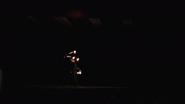 Two guys from the fire show are spinning fire chains from behind, The guy in front is breathing fire