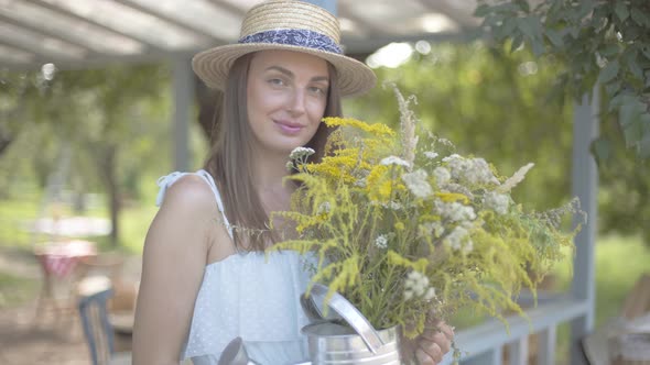 Portrait Pretty Young Woman in Straw Hat and White Dress Looking at the Camera Smiling While Holding