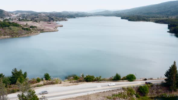 Aerial: Half Moon Bay Lake, Landscape and Cars. Flying Backward