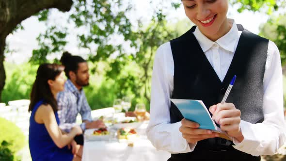 Waitress writing on note pad at outdoor restaurant