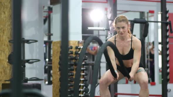 Young woman doing some crossfit exercises with a rope